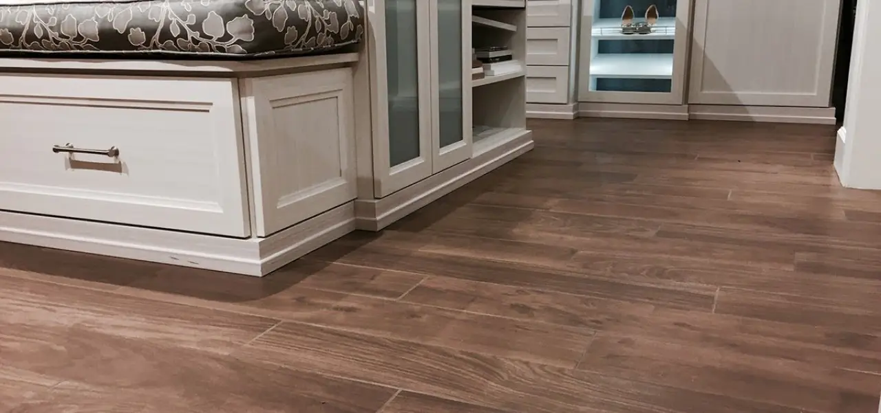 Brown wood-look porcelain tile flooring in a white dressing room.