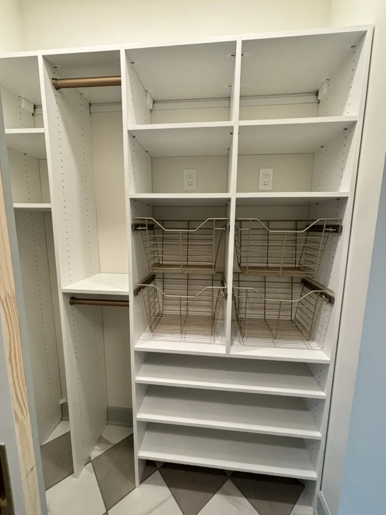 White closet organizer with shelves, wire baskets, and hanging rods in an empty walk-in closet.