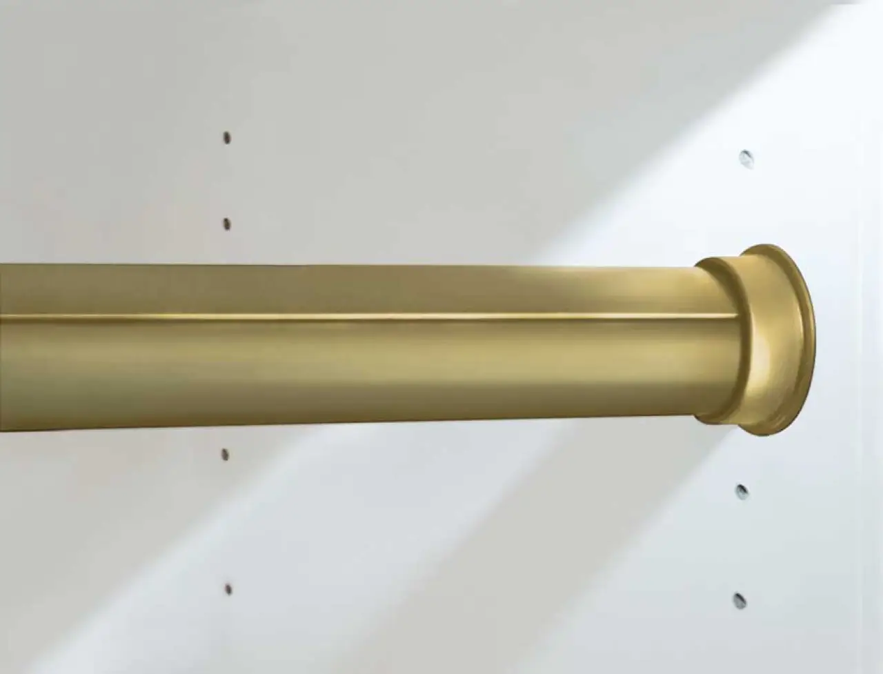 Close-up of a gold-colored curtain rod installed on a white wall with mounting holes visible.