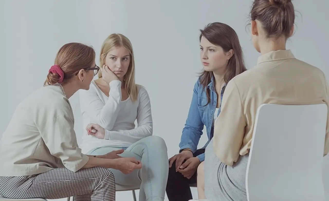 four women sitting together talking in a circle