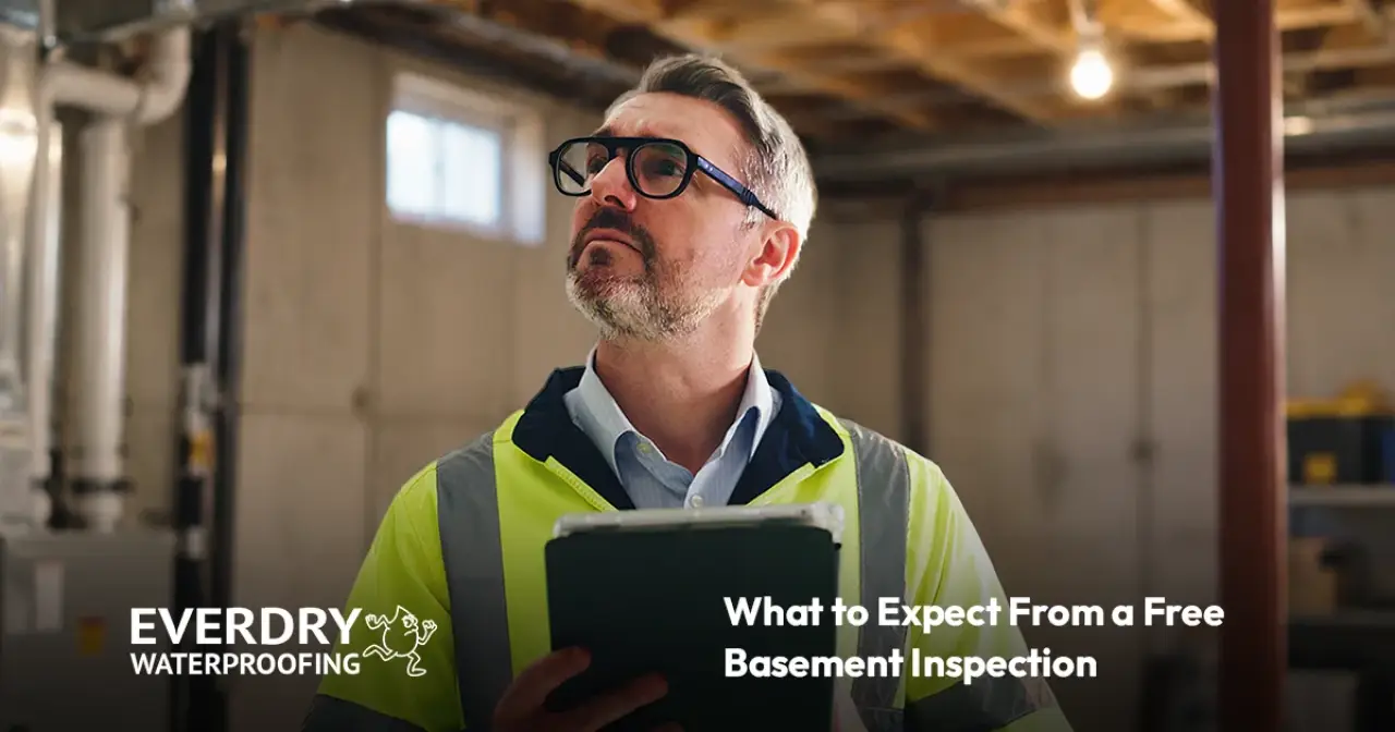 Inspector in a high-visibility vest holding a tablet in an unfinished basement.