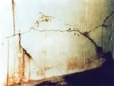 Cracked and stained wall with dark marks and patches of discoloration near the bottom edge.