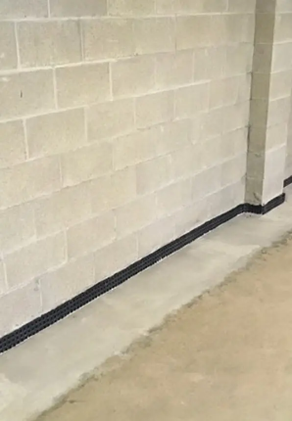 Beige concrete basement wall with a black stripe along the bottom