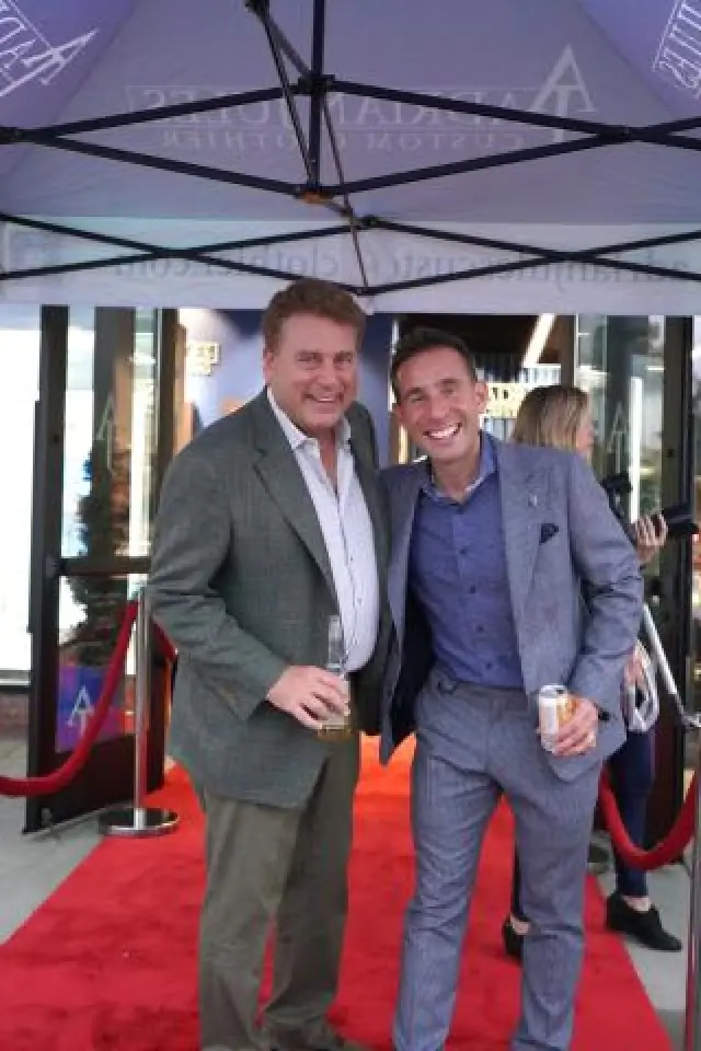 Two men in suits celebrate together on a red carpet.