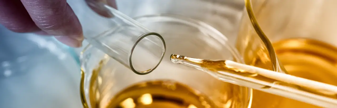 Amber extract being transferred between lab glassware.