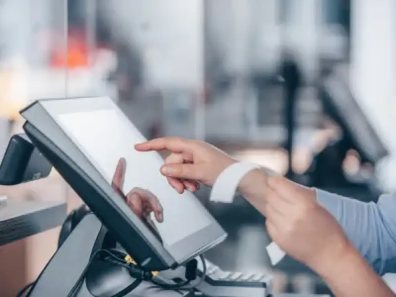 Person using a touchscreen point-of-sale system while holding a receipt in one hand.