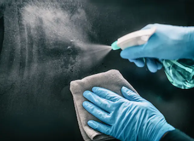 person with blue gloves spraying glass
