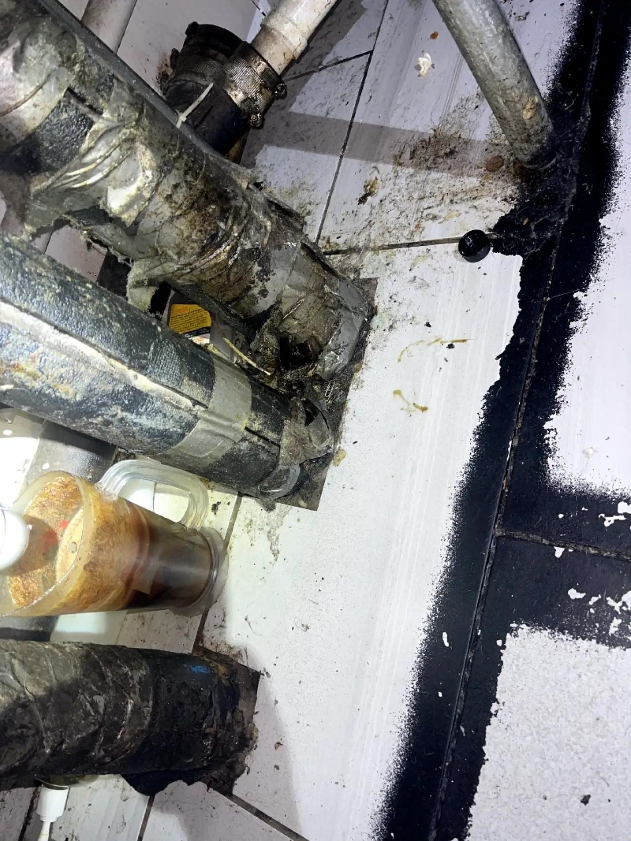 Grimy utility area around exposed pipes before commercial cleaning.