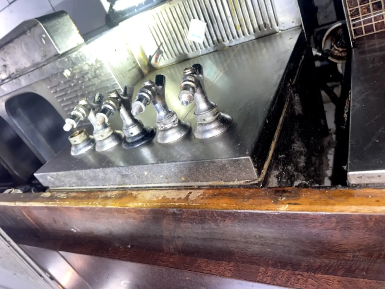 Commercial kitchen stovetop with removed burners and visible grease buildup.