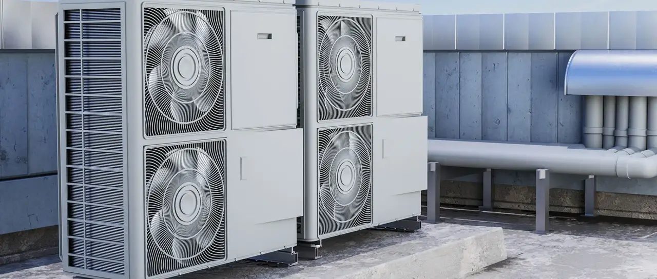 Two large outdoor HVAC units sit on a rooftop near pipes and a blue wooden wall.