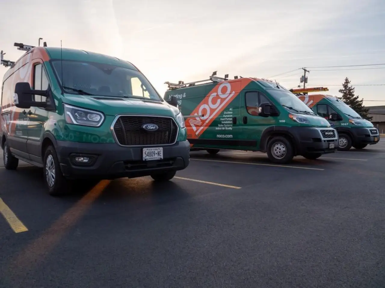 NOCO service vans parked in a row at sunrise