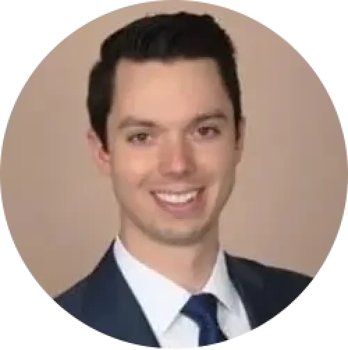 smiling man in a suit and tie against a beige background