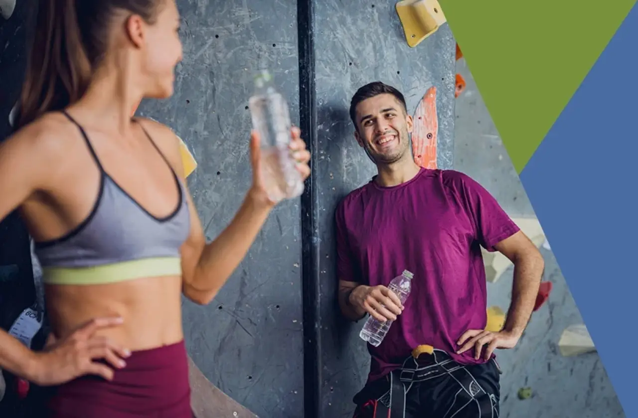two people with water bottles taking a break from indoor rock climbing