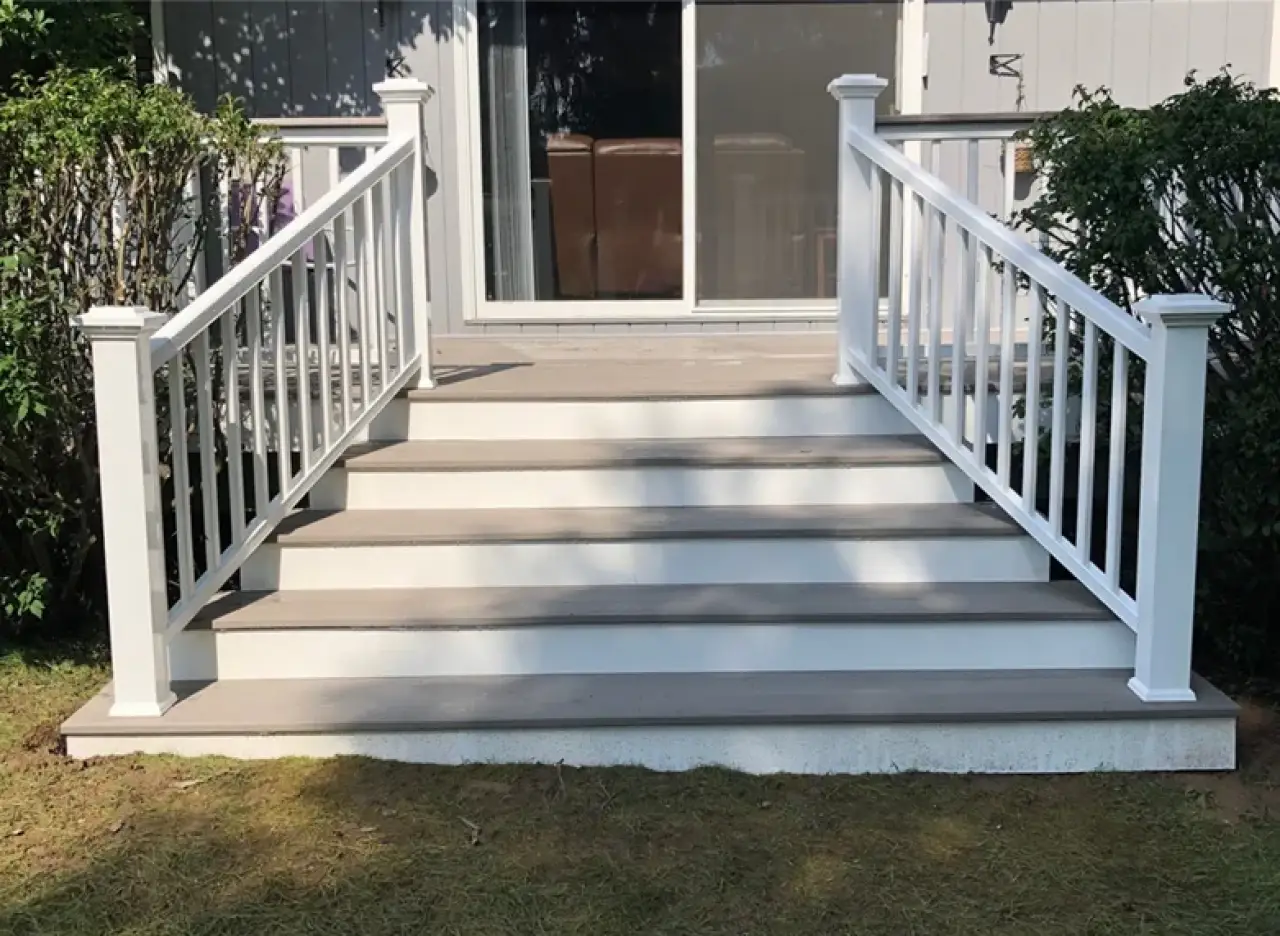 Composite deck stairs with white railings leading to sliding patio doors.