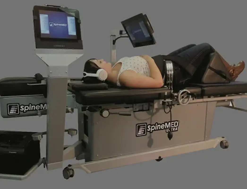 person lying on SpineMED Ultra table, wearing headphones, for spinal decompression therapy