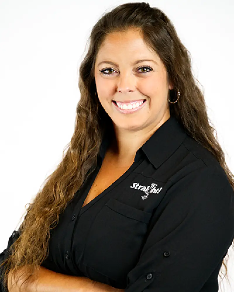 Smiling woman with long brown hair, wearing a black shirt, posed against a white background.