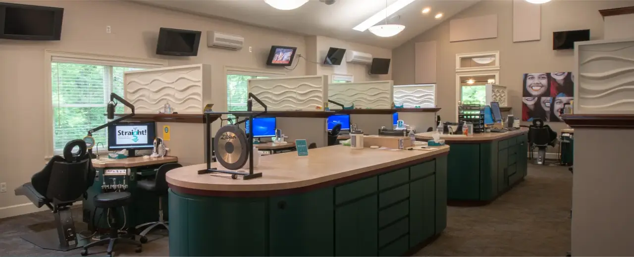 Modern dental office with green cabinets, computer stations, and partitioned workspaces.