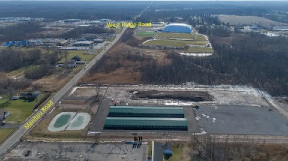 Aerial view of intersections West Ridge Road and Manitou Road, with buildings and open land.