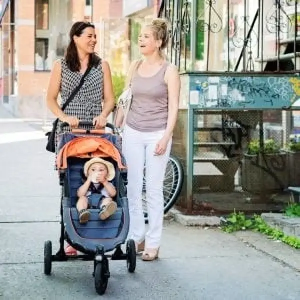 A mom and her friend chatting while on a walk and pushing a baby in a stroller