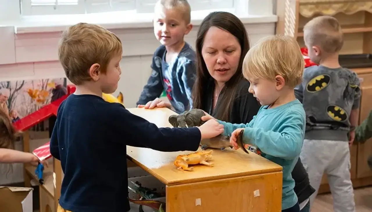 Toddlers playing with animal figurines on a table.