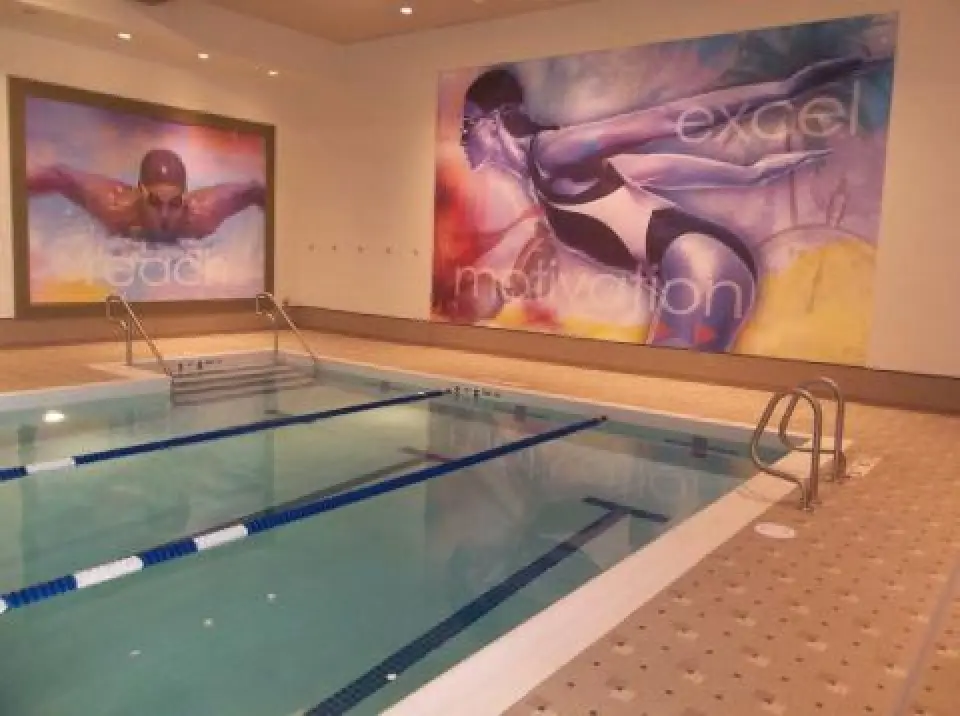 Indoor swimming pool with large motivational swimmer murals on the walls.