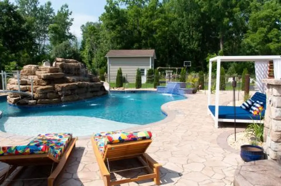 Residential pool with rock waterfall, sun shelf, lounge chairs, and cabana.