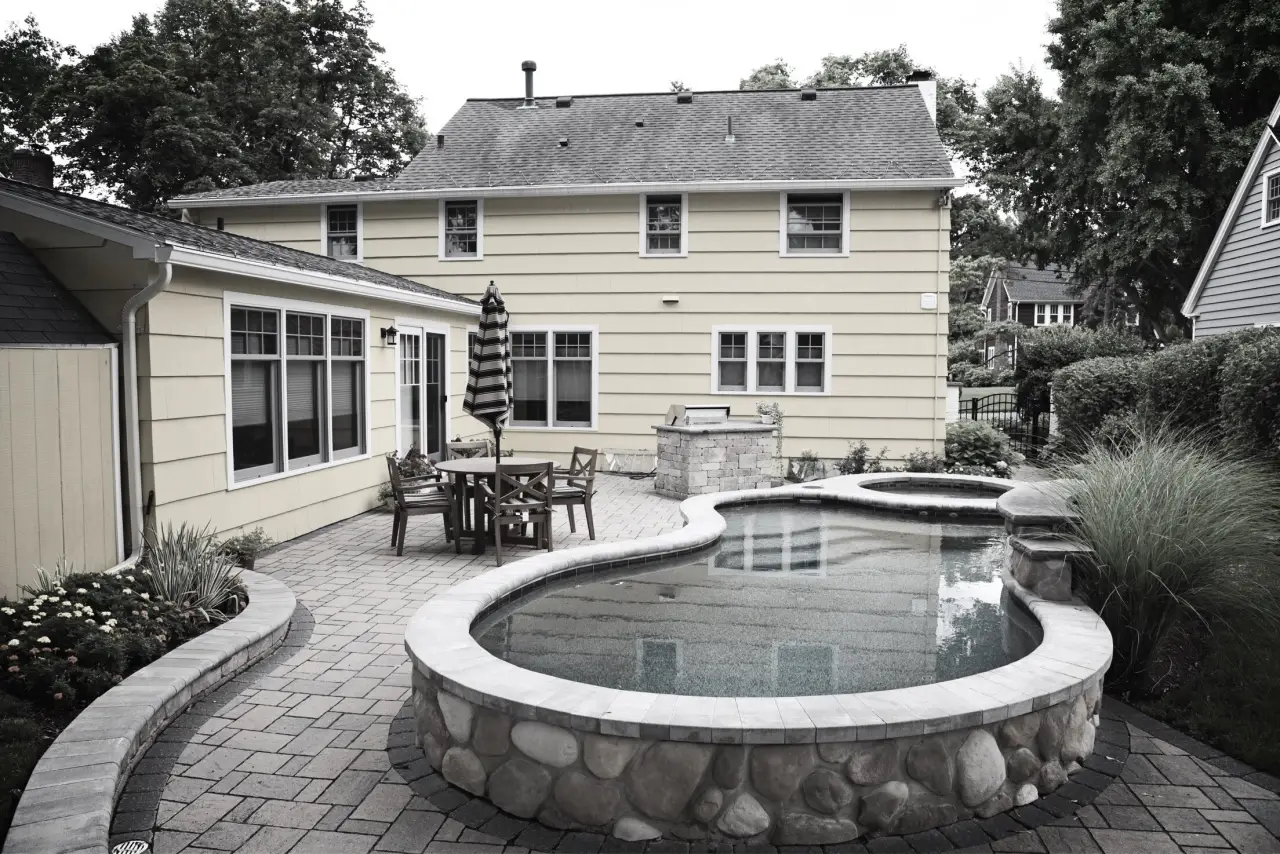 backyard with curved pool, spa, and patio table