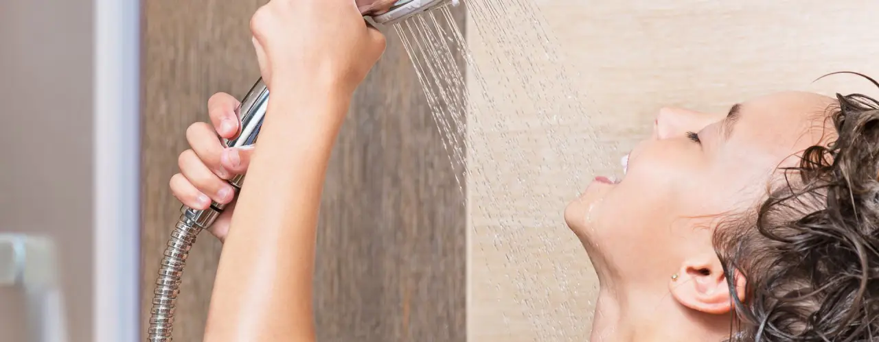 Person enjoying hot water from a tankless water heater in Rochester NY