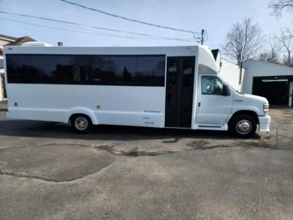 White limo bus parked outside with tinted panoramic windows.