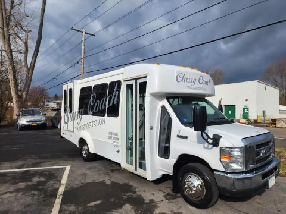White Classy Coach wheelchair-accessible shuttle bus parked outdoors.