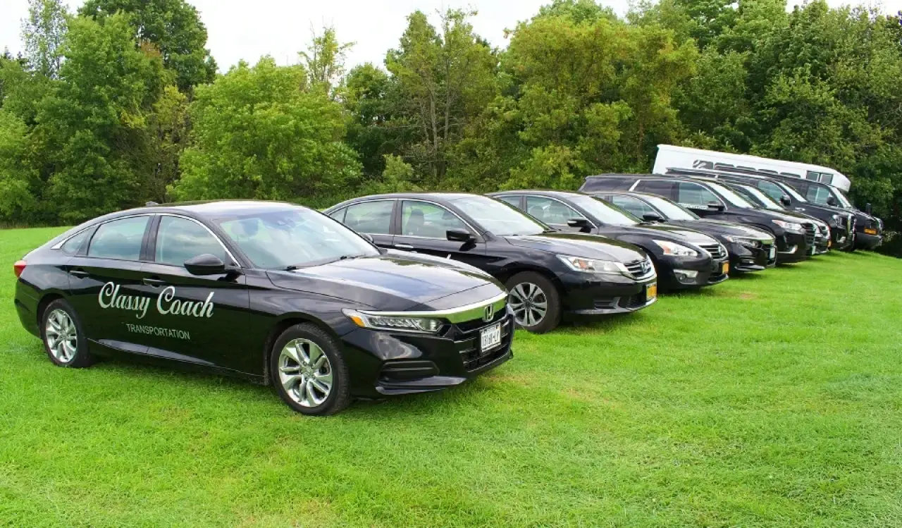 Classy Coach black car fleet parked on a grassy lawn.