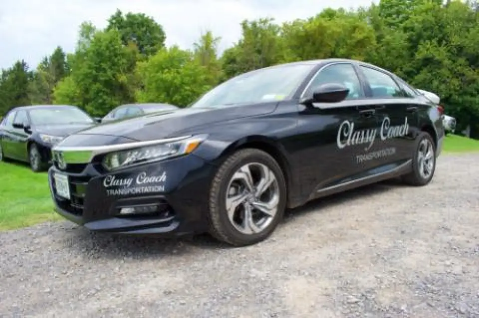 Black Classy Coach sedan parked on a gravel lot.