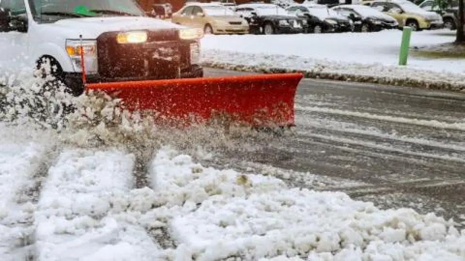 white truck with red plow pushing slushy snow
