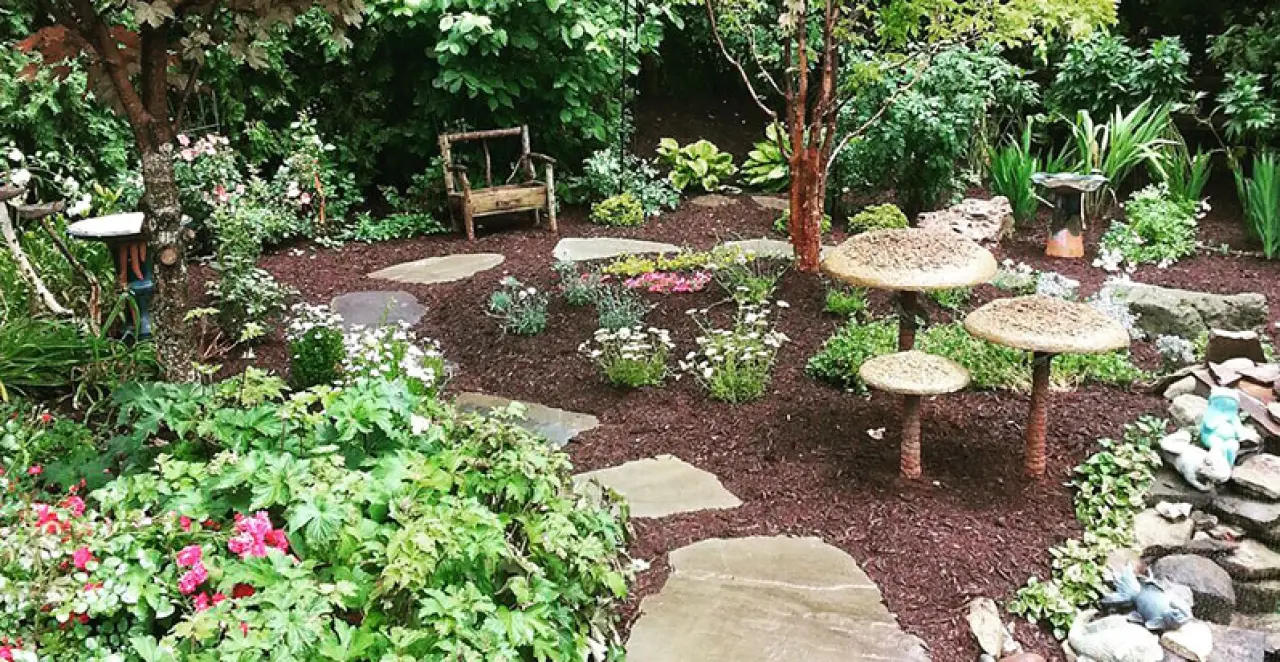 beautiful landscape garden with mulch, stone steps, stone mushroom accents, and flowerbeds