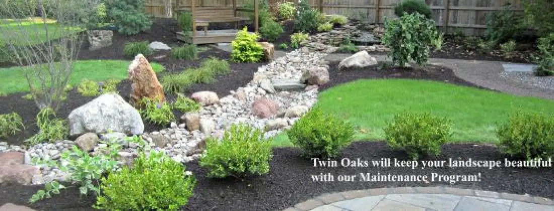 beautiful landscape with rocks and mulch "twin oaks will keep your landscape beautiful with your Maintenance Program!"
