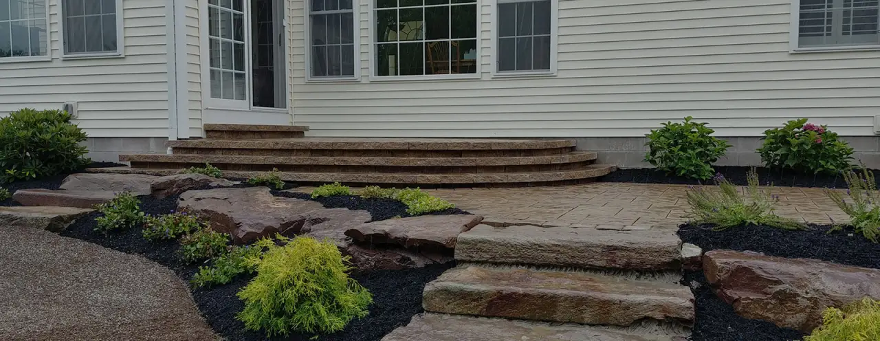 back steps of house made of smooth stone surrounded by mulch and stone steps