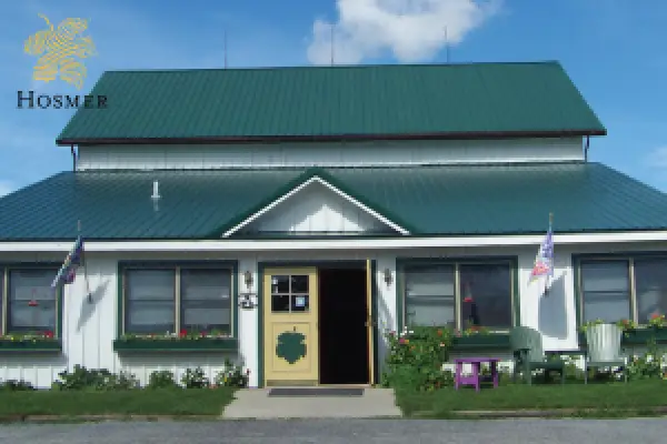 The Hosmer Winery tasting room, a pale building with a green roof and flags beside the door