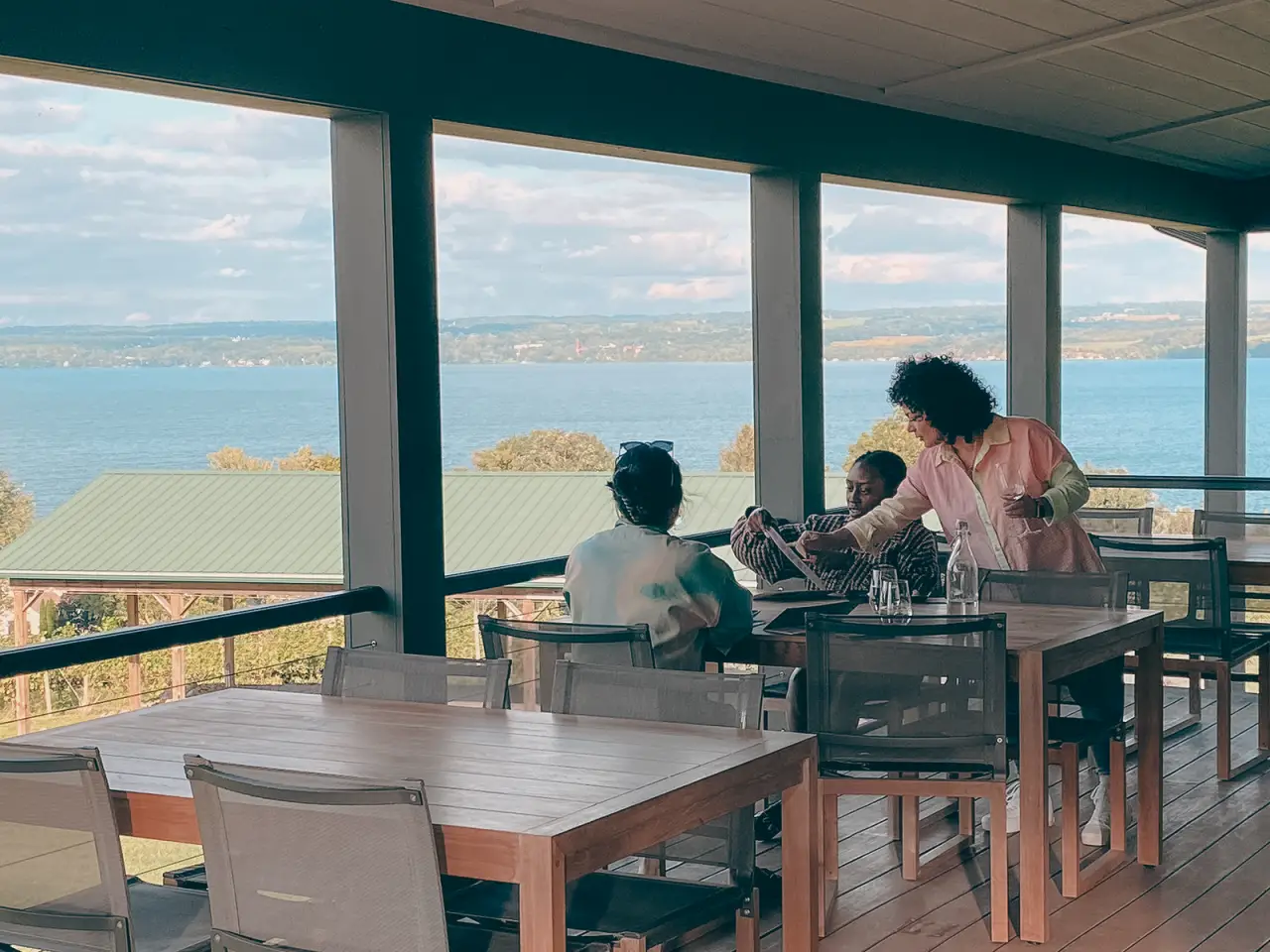 Guests seated at tables in front of the tasting room's lake-facing windows