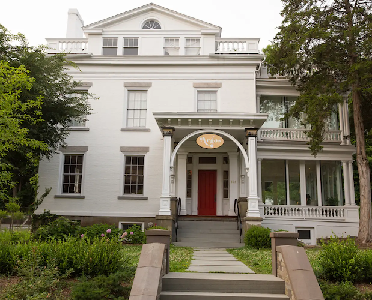 White historic building with a red door, arched entry, and a Argos sign above the entrance.