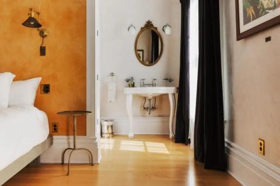 cozy bedroom with a vintage sink, mirror, and an orange accent wall