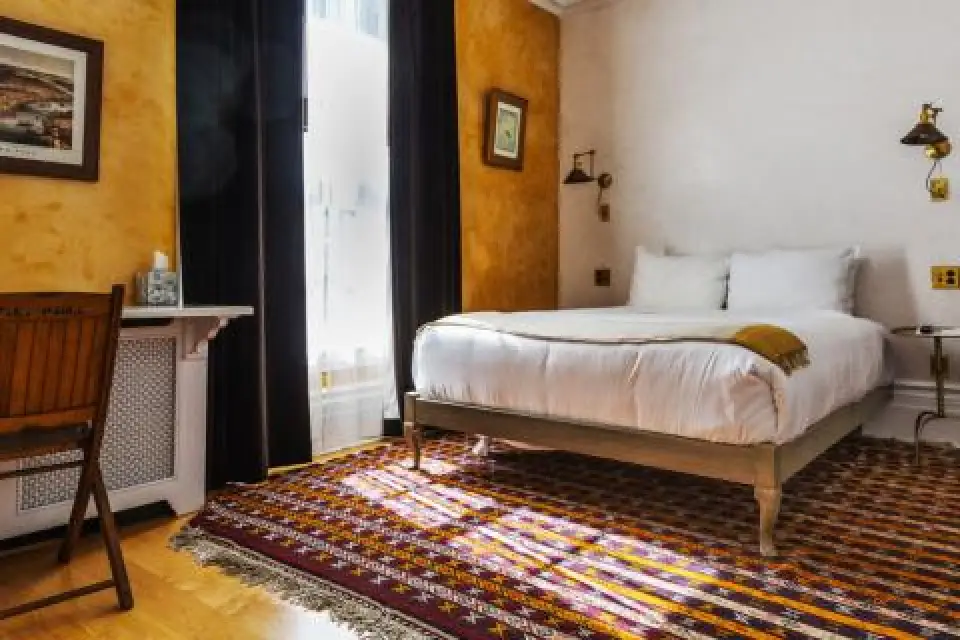 cozy hotel room with a double bed patterned rug and sunlight streaming through a window