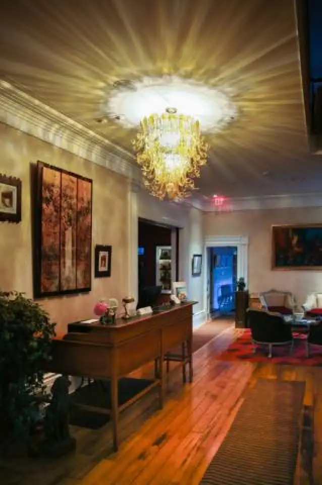 elegant hallway with a chandelier, wooden floor, and art on walls, leading to a cozy room