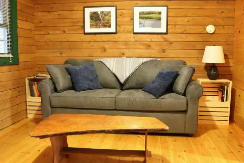 A cozy living room with a gray sofa, blue pillows, wooden table, and pictures on the wall.