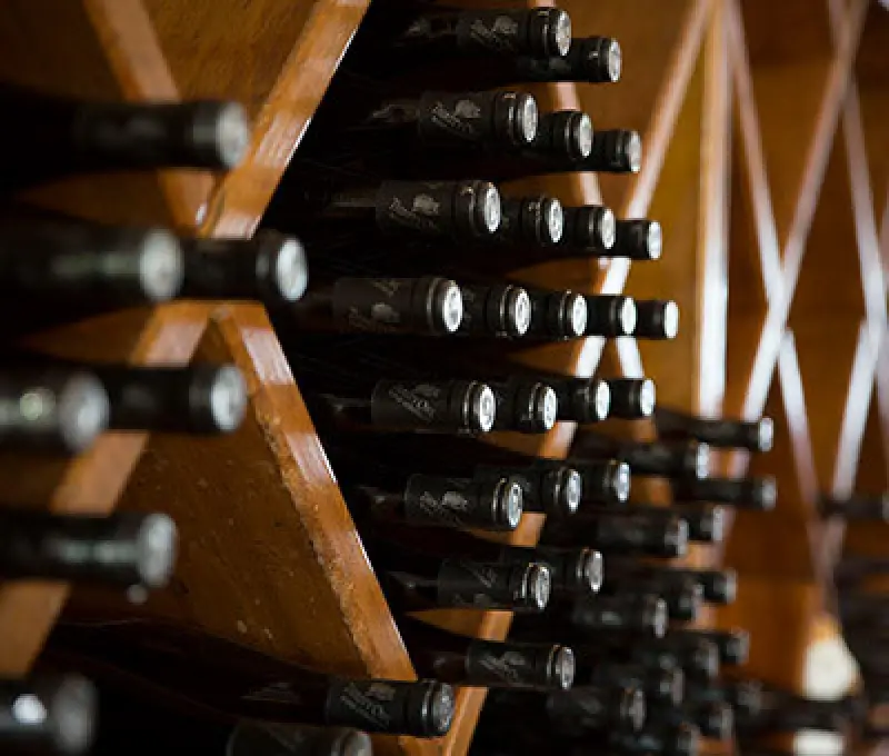 wine bottles stored horizontally in a wooden rack, viewed from an angled perspective