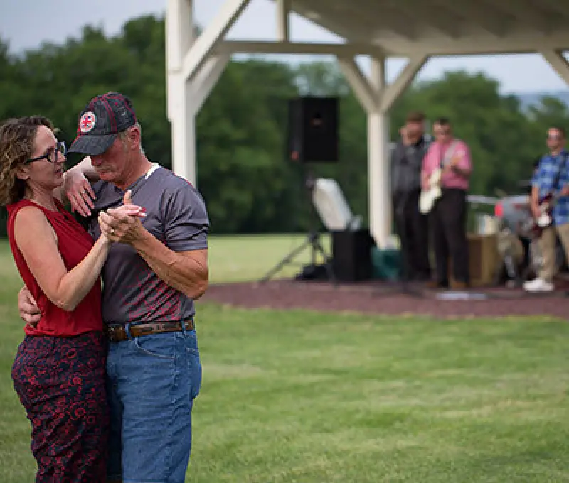 couple dancing outdoors while a band plays in the background
