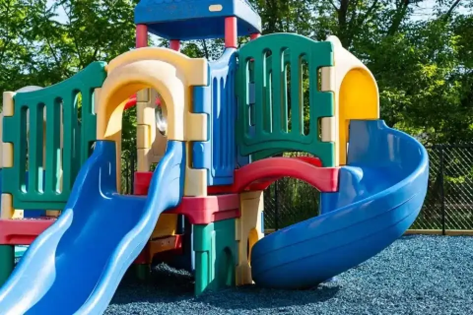 Colorful playground structure with slides and climbing areas on a rubber surface, outdoors.