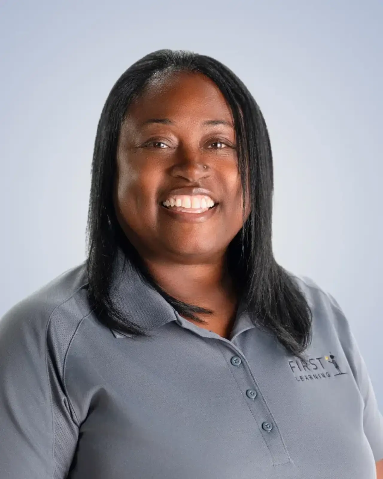 Smiling woman with straight black hair in a gray polo shirt against a light background.