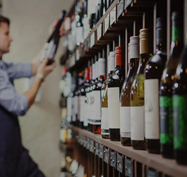 customer in the background holds and examines a bottle of wine