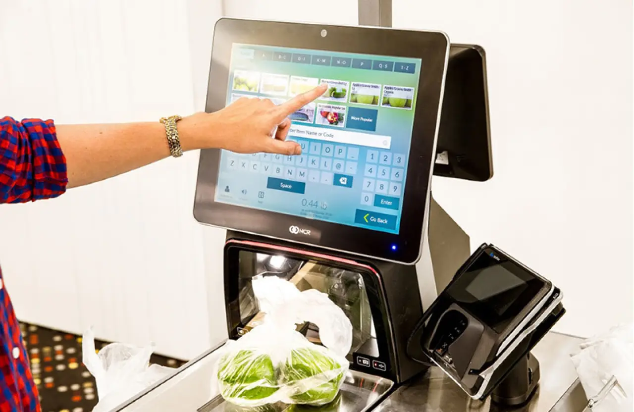 woman in plaid shirt pointing at NCR Encor POS System