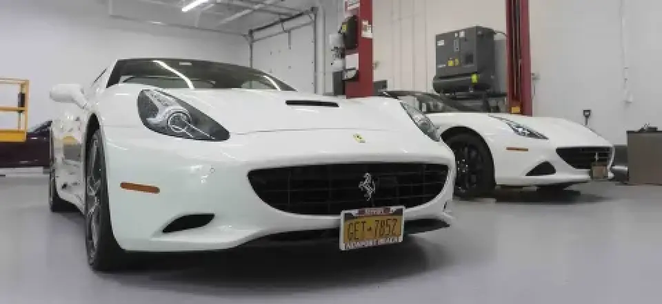 Two white Ferrari cars parked inside a clean, modern garage with bright lighting.